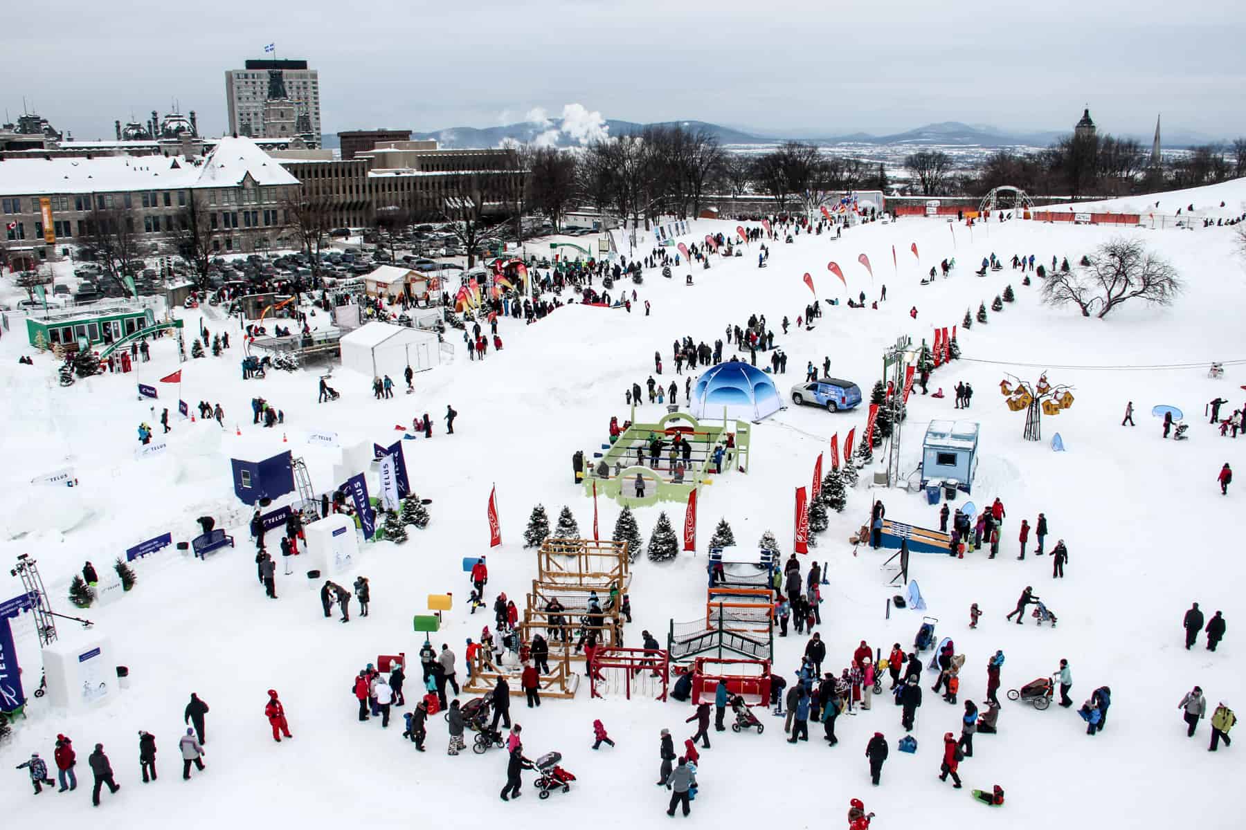 An elevated view of Quebec City's Plains of Abraham covered in snow, tents and people enjoying the Carnival de Quebec. 