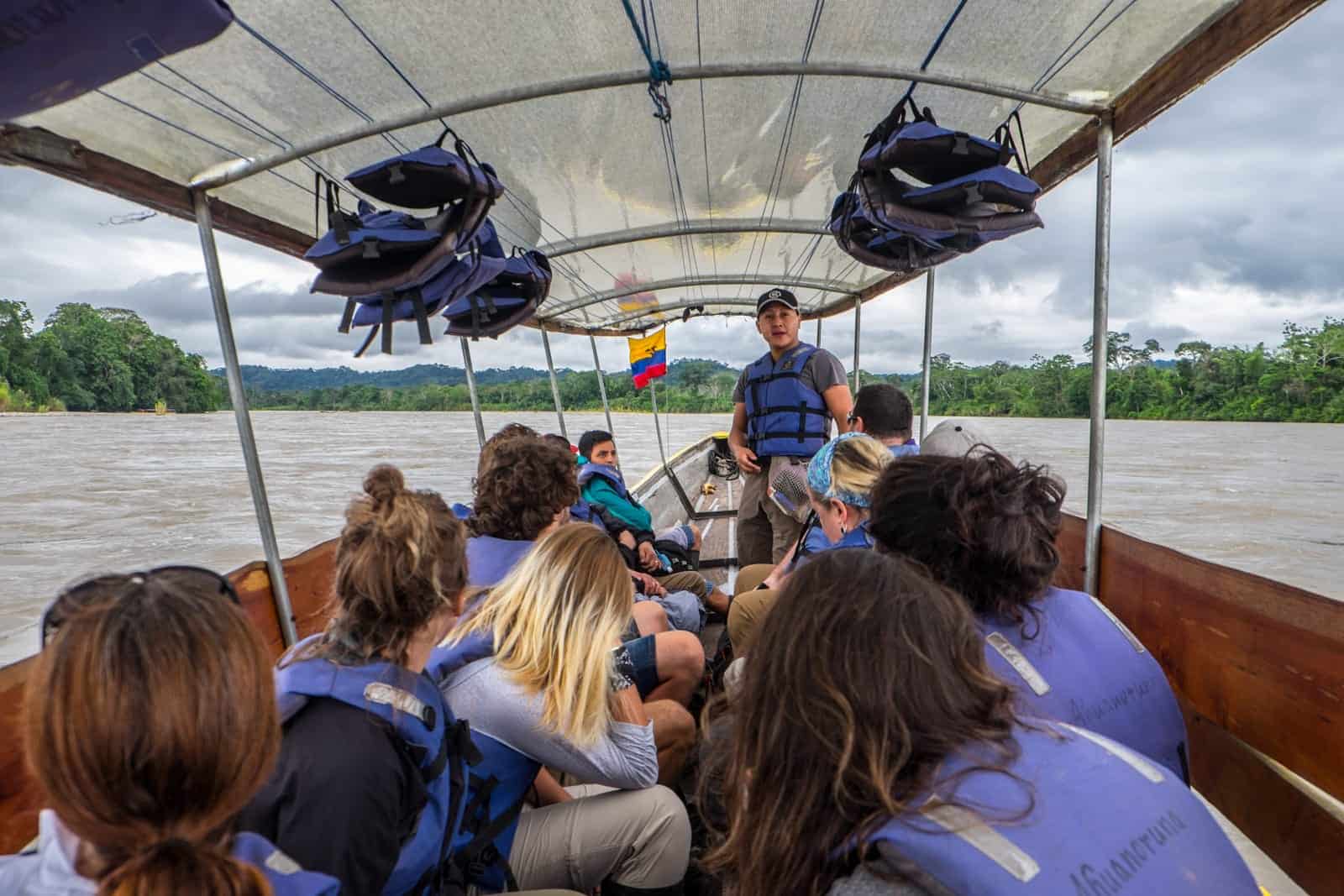 A small group of people on a Longboat ride on the wide Ecuador Amazon River. 
