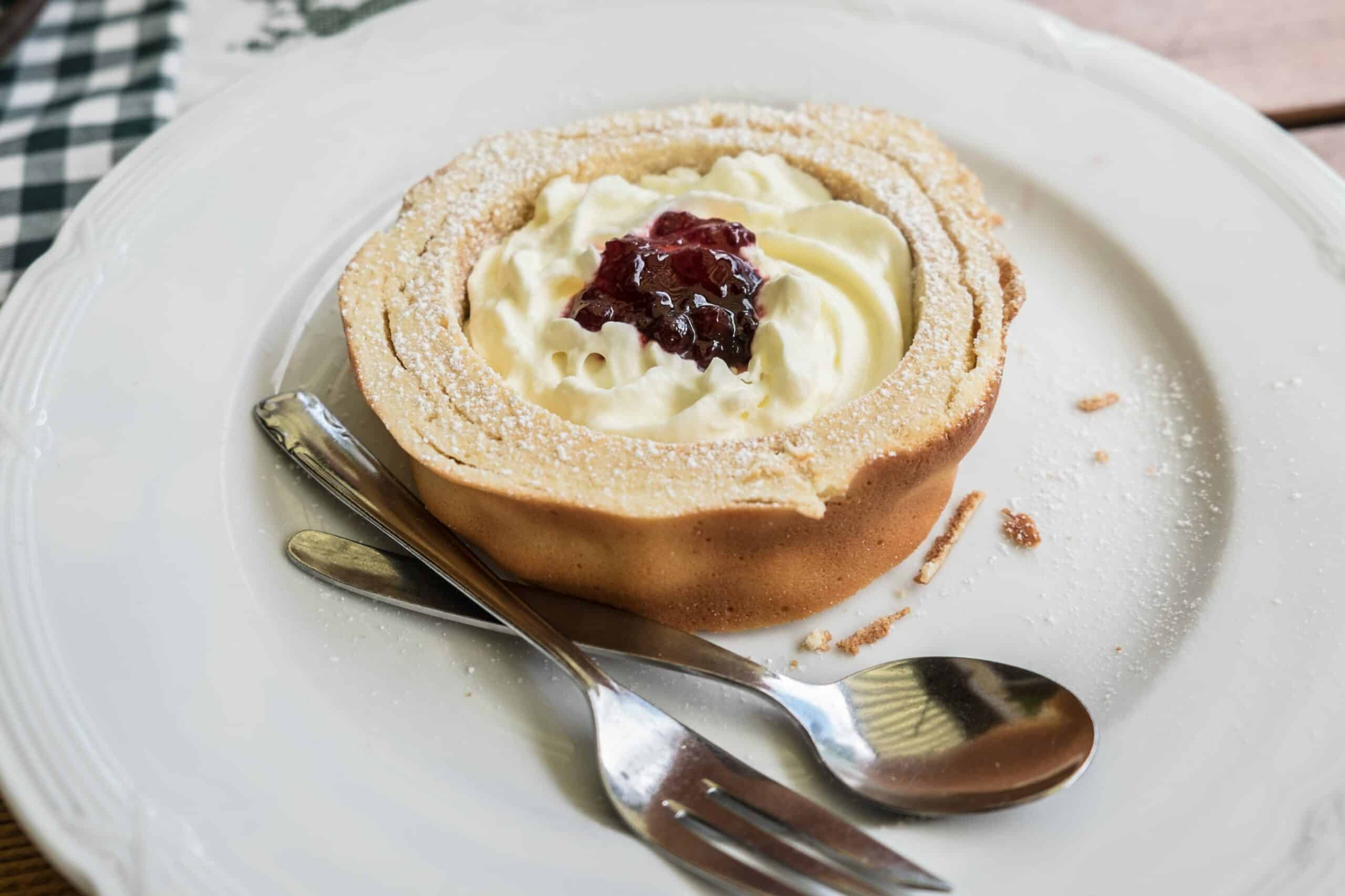 A round slice of Prügeltorte cake, filled with cream and topped with jam. 