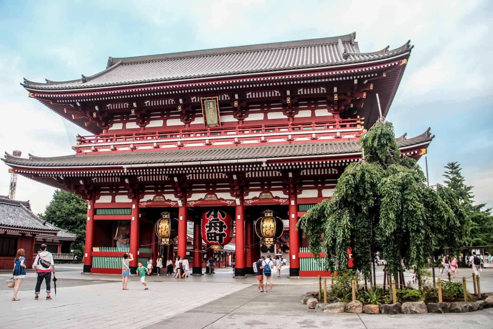 People walking through the two-tiered red columned Sensoji Temple in Tokyo. 