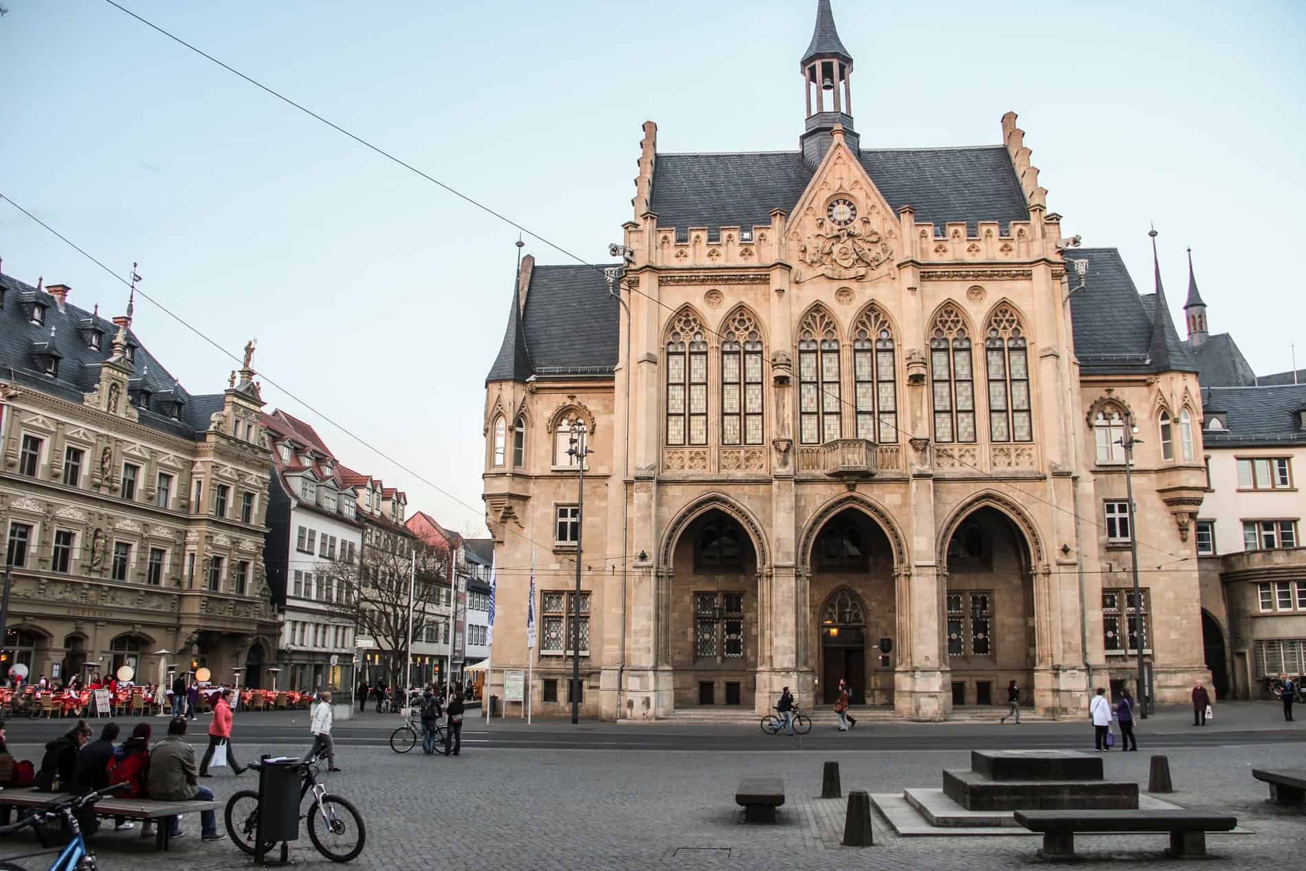 Erfurt's neo-Gothic City Hall intricate mocha stone carvings and black roof , set on a cobblestoned square. 